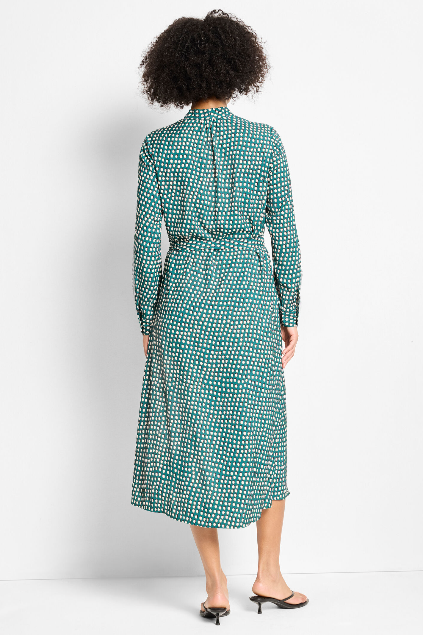 Woman wearing a green patterned dress on a white background