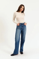 Woman wearing a white sweater and blue jeans on a white background
