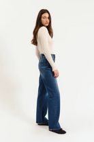 Woman wearing blue jeans and a white top on a white background