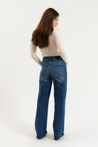 Woman wearing blue jeans and a beige sweater on a white background
