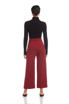 Person wearing a black turtleneck and red pants on a white background