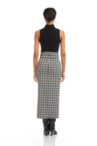 Person wearing a black sleeveless top and plaid skirt on a white background