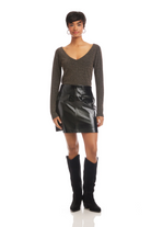Woman wearing a brown long-sleeve top and black leather skirt with knee-high black boots on a white background