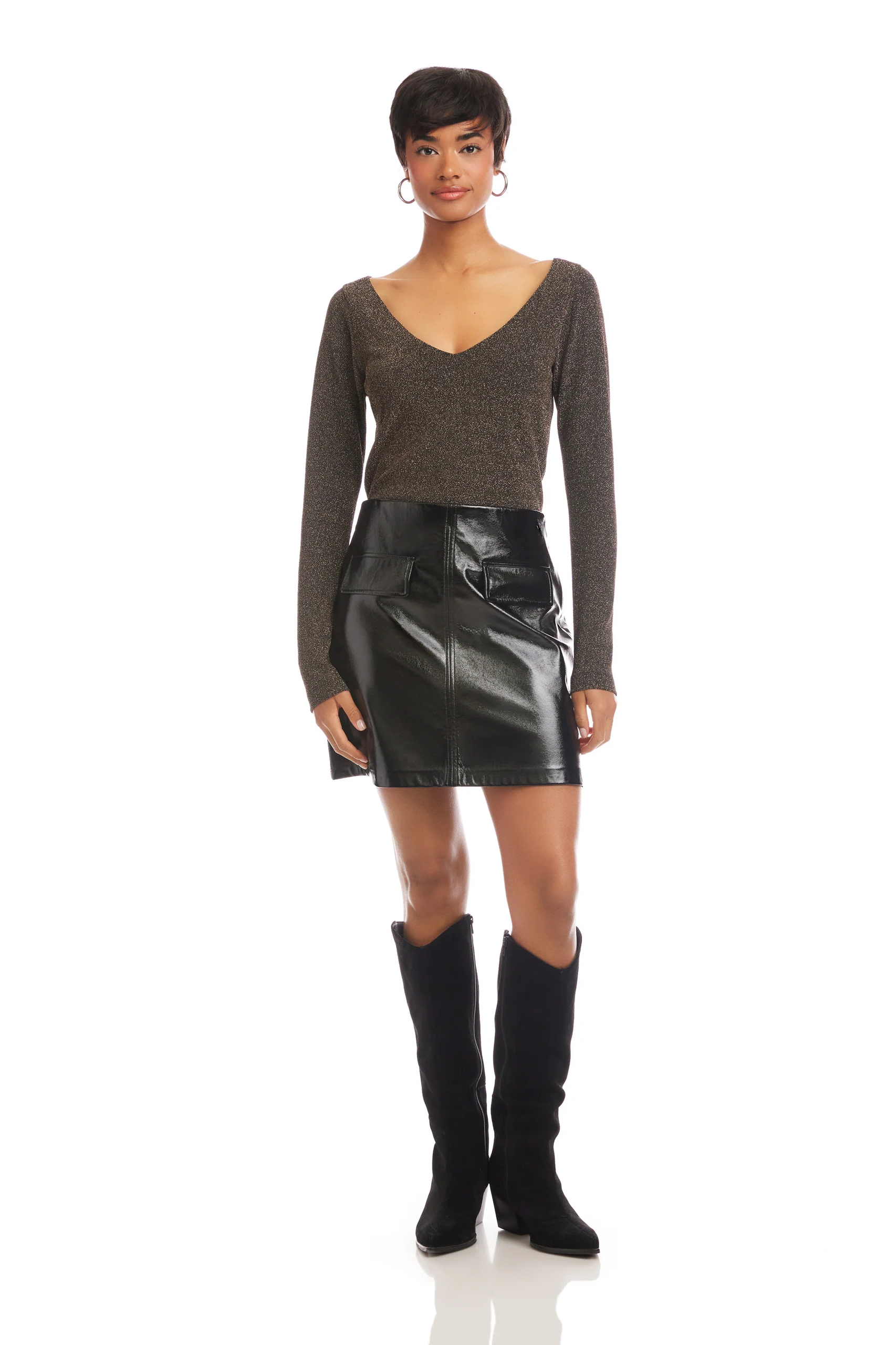 Woman wearing a brown long-sleeve top and black leather skirt with knee-high black boots on a white background