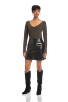 Woman wearing a brown long-sleeve top and black leather skirt with knee-high boots on a white background