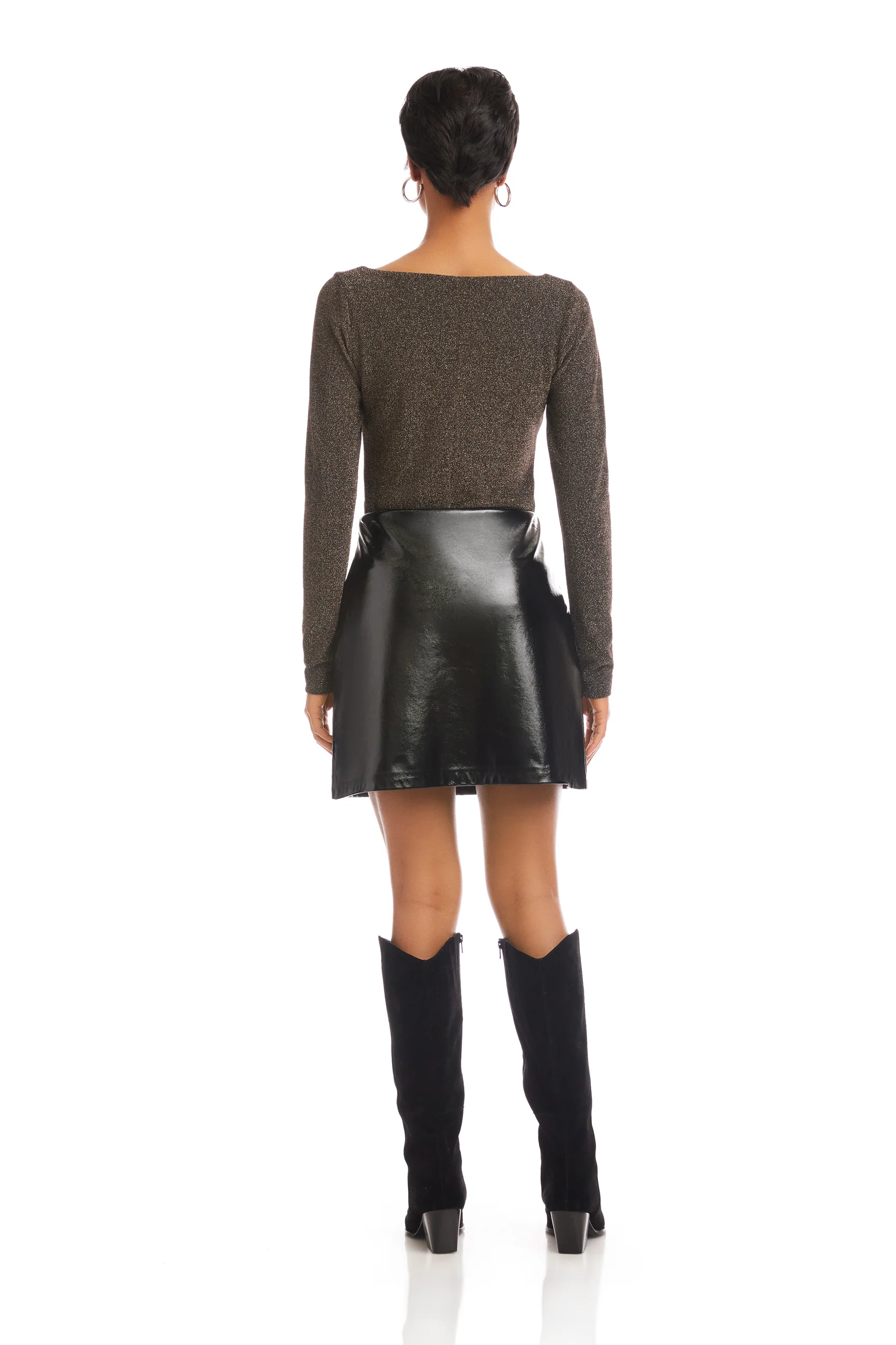 Person wearing a brown long-sleeve top and black leather skirt on a white background