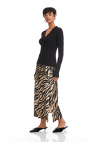 Woman wearing a black top and zebra print skirt on a white background