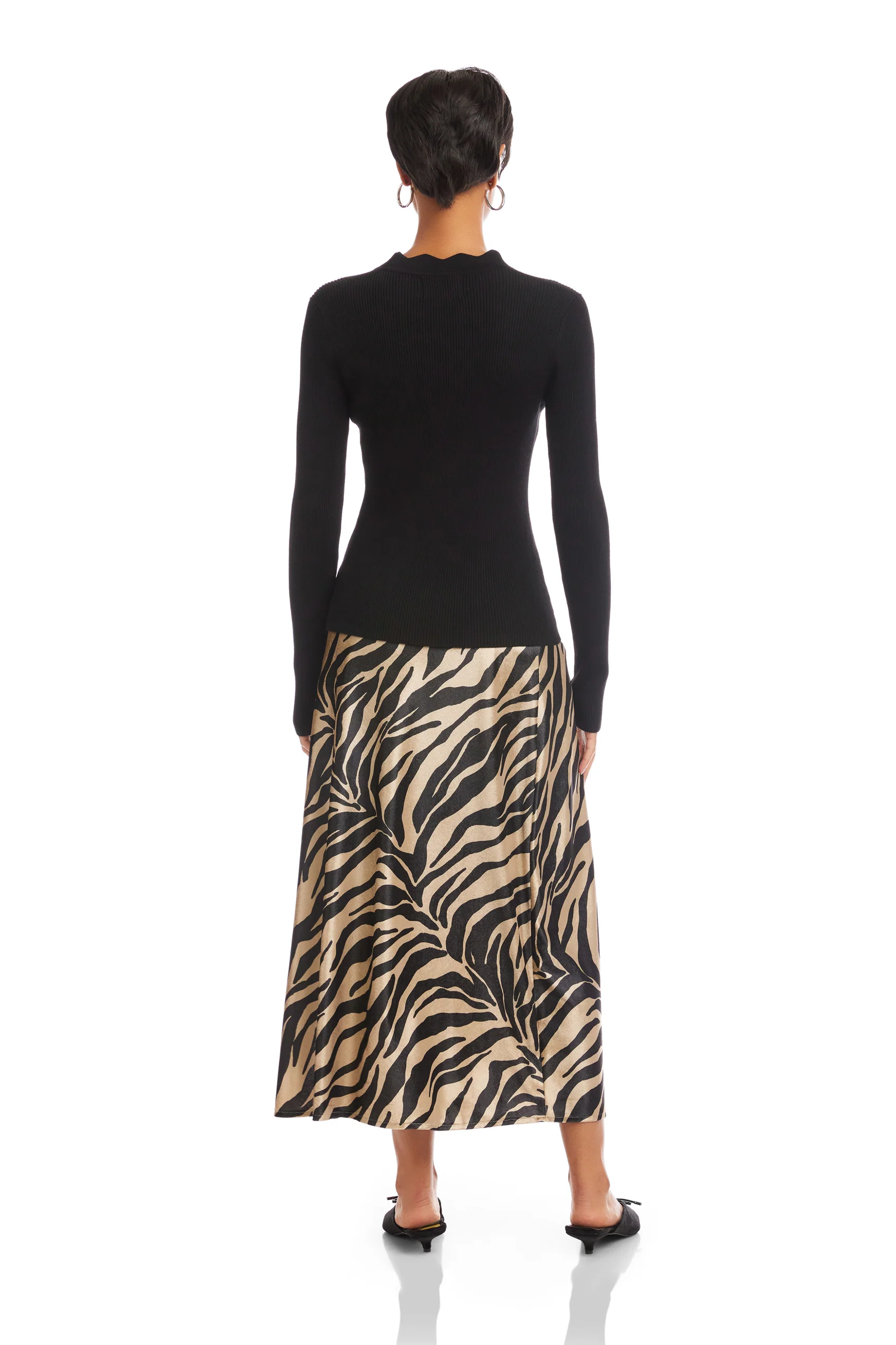 Person wearing a black long-sleeve top and a zebra-patterned skirt on a white background