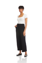 Woman wearing a white top and black wide-leg pants on a white background