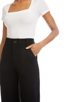 Person wearing a white top and black high-waisted pants on a white background