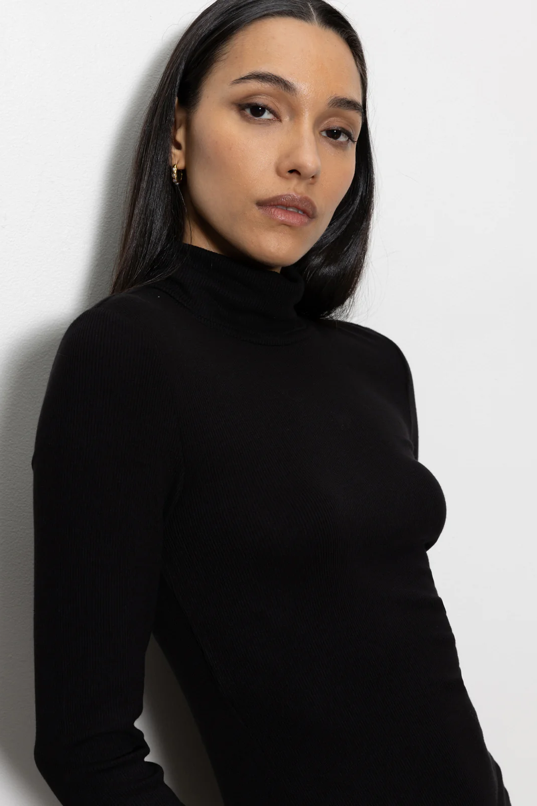 Woman wearing a black turtleneck against a white background