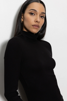 Woman wearing a black turtleneck against a white background