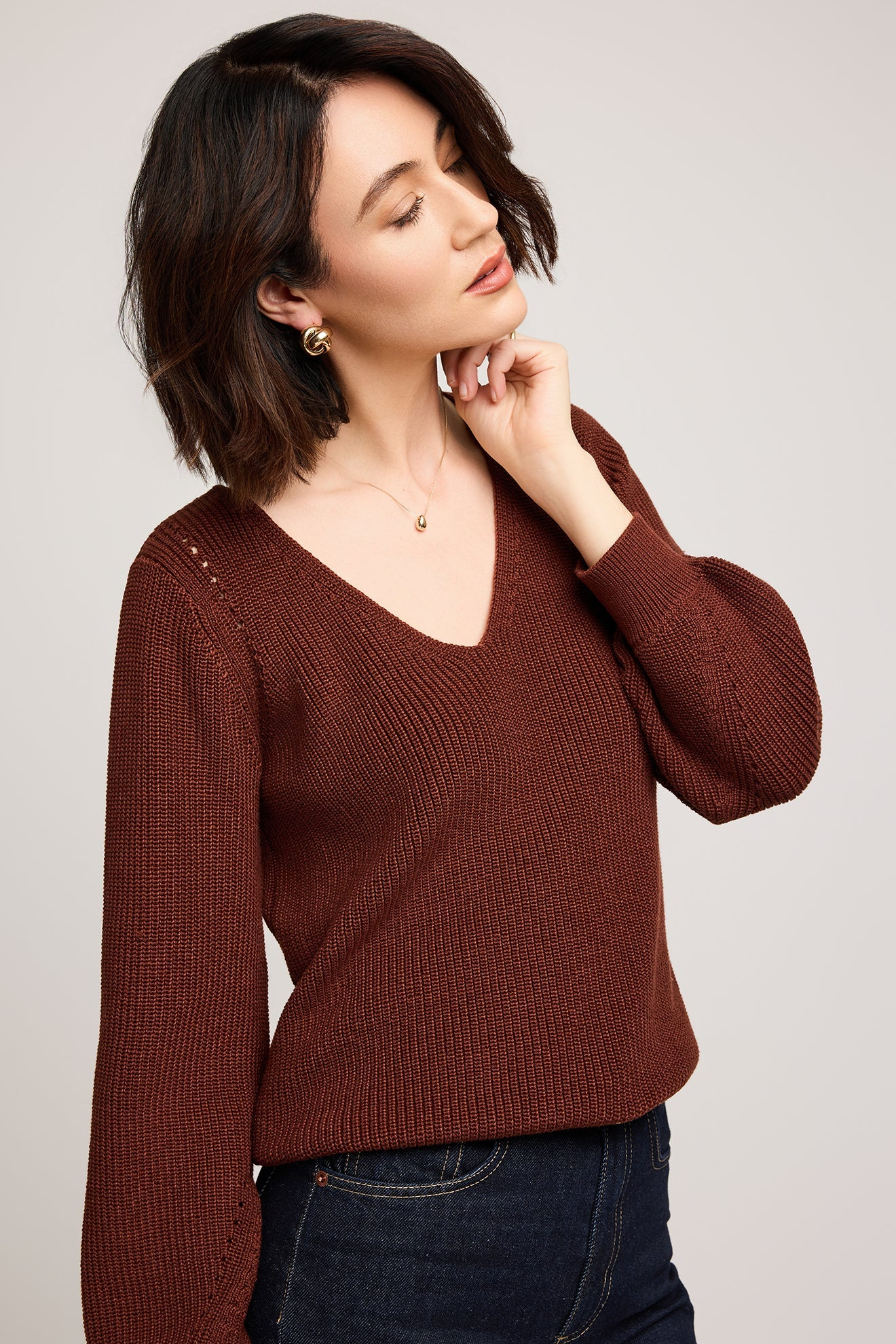Woman wearing a brown sweater against a plain background
