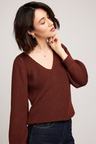 Woman wearing a brown sweater against a plain background