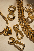 Gold jewelry including chains, rings, and pendants on a beige background