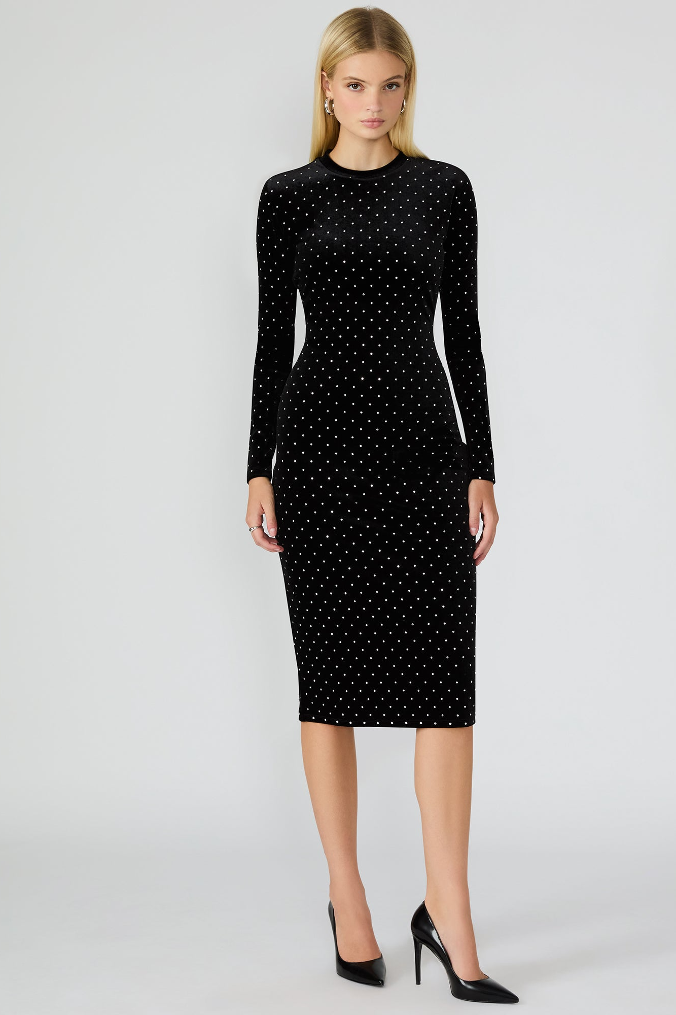 Woman wearing a black dress with white polka dots on a white background
