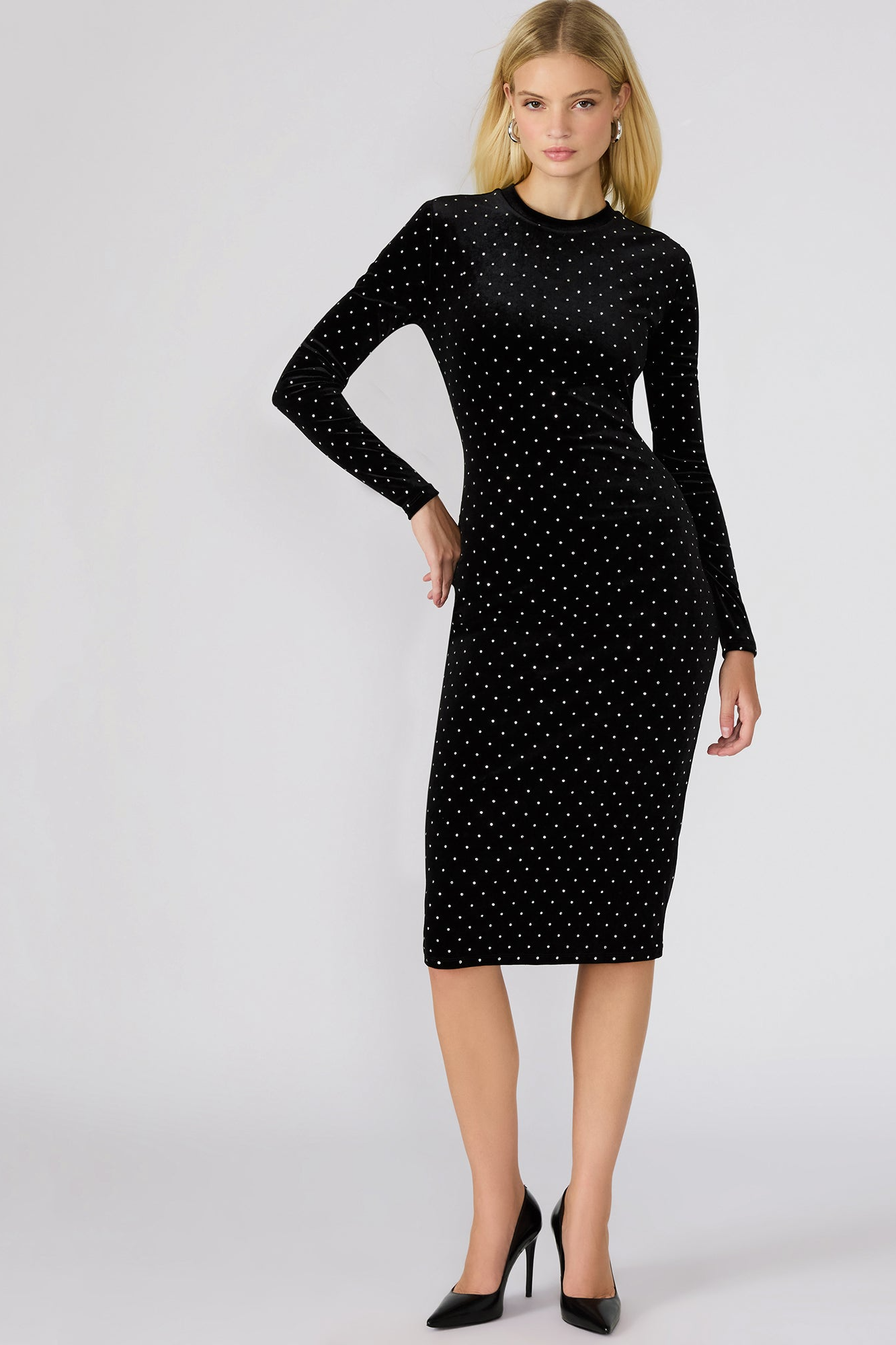 Woman wearing a black dress with white polka dots on a white background