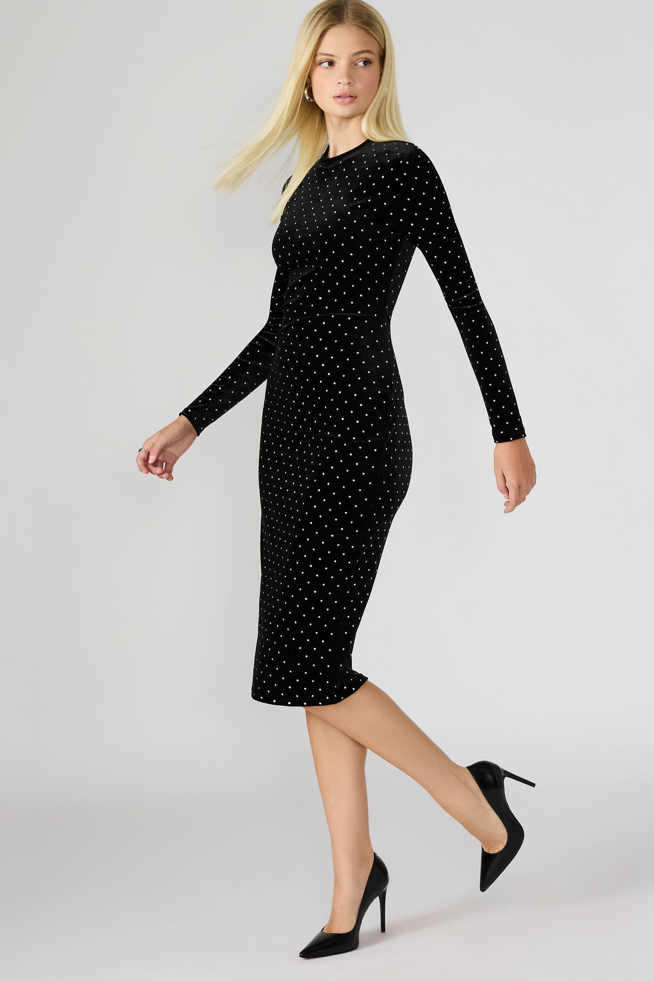 Woman wearing a black dress with white polka dots on a light gray background