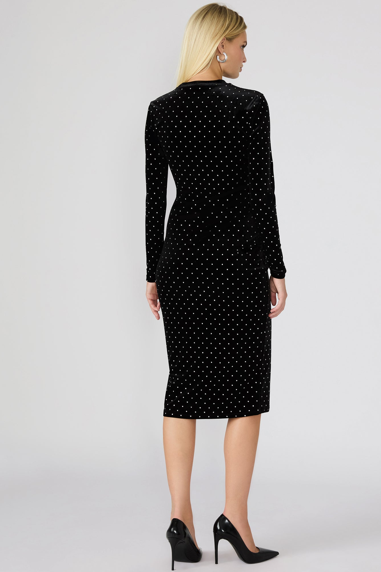 Woman wearing a black dress with white polka dots on a white background