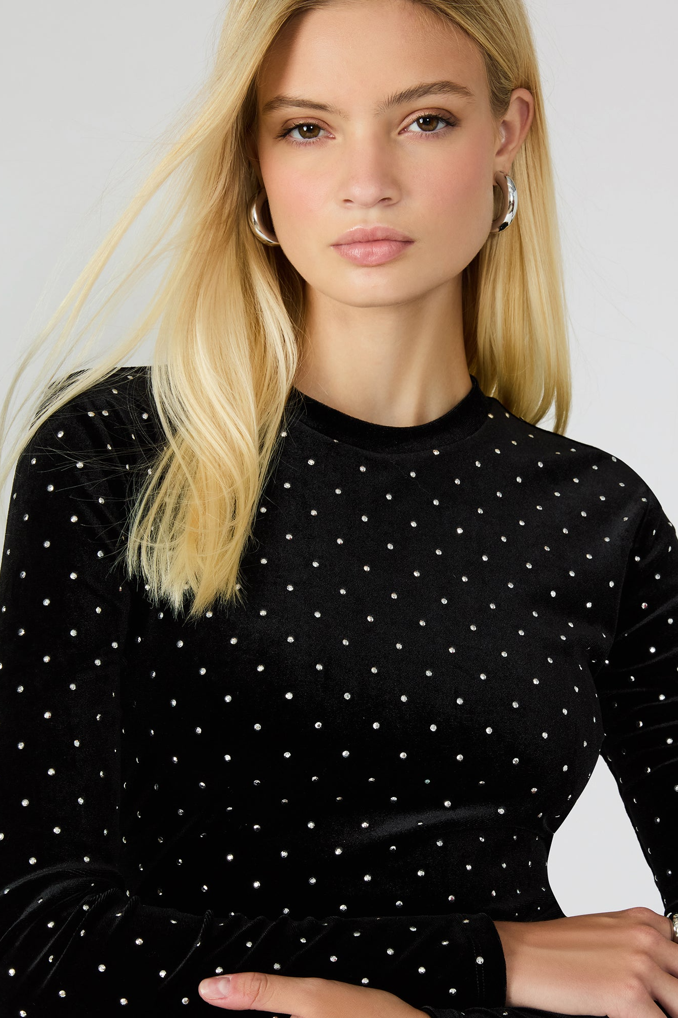 Woman wearing a black polka dot dress against a plain background