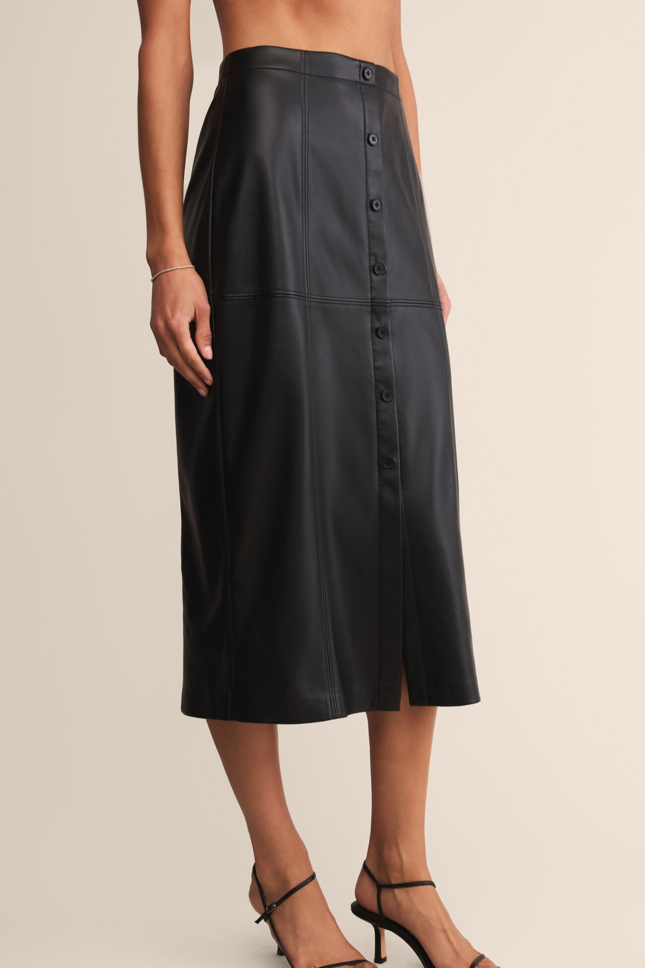 Black button-up skirt worn by a person on a beige background
