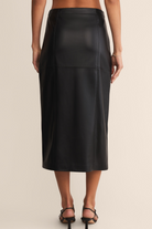 Black leather skirt worn by a person on a beige background