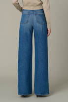 Person wearing blue wide-leg jeans on a neutral background