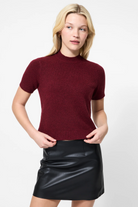 Woman wearing a burgundy sweater and black leather skirt on a white background