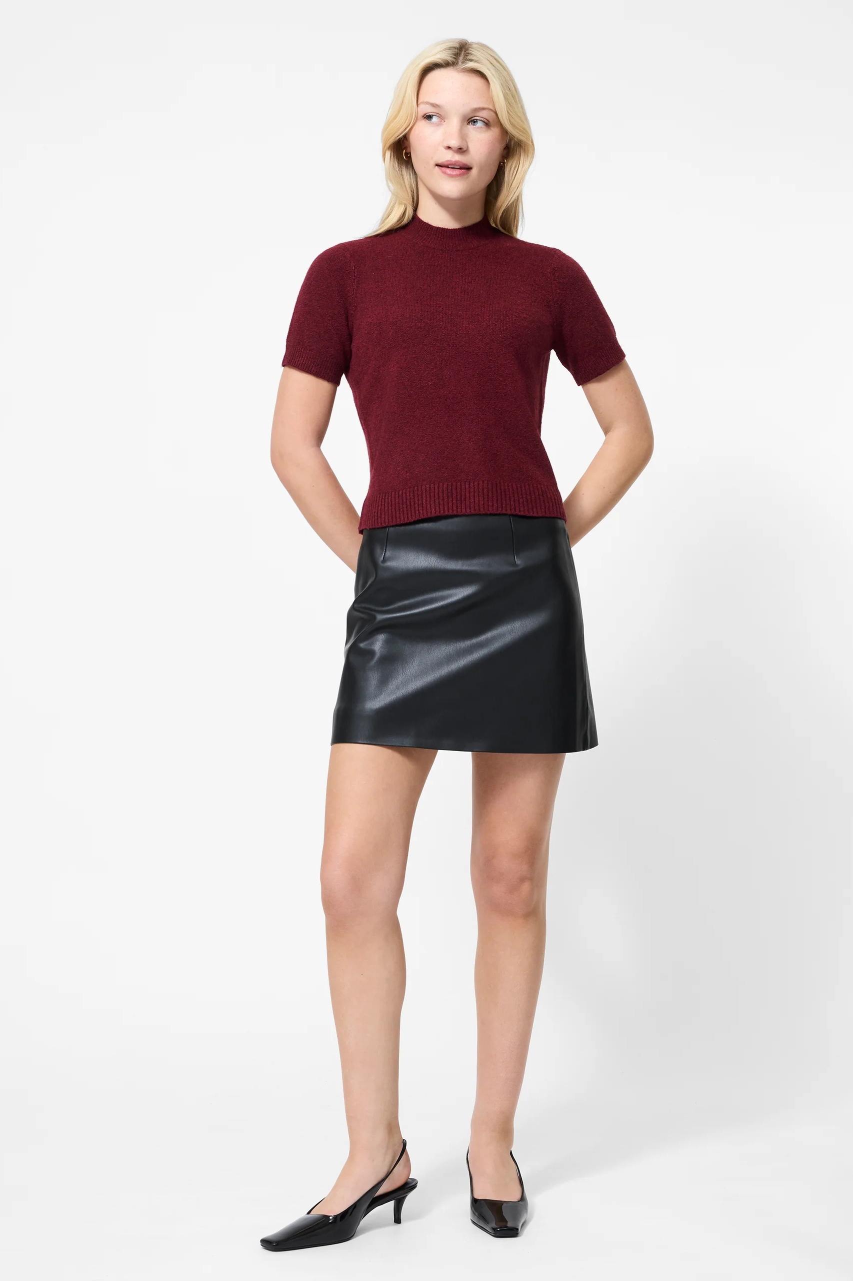 Woman wearing a burgundy top and black leather skirt on a white background