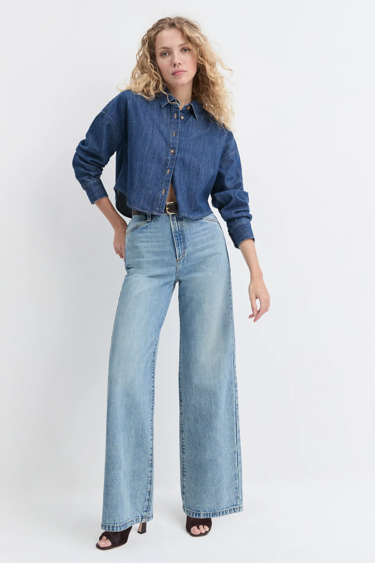 Woman wearing a denim jacket and light blue jeans on a white background