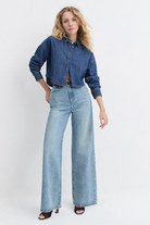 Woman wearing a denim jacket and light blue jeans on a white background