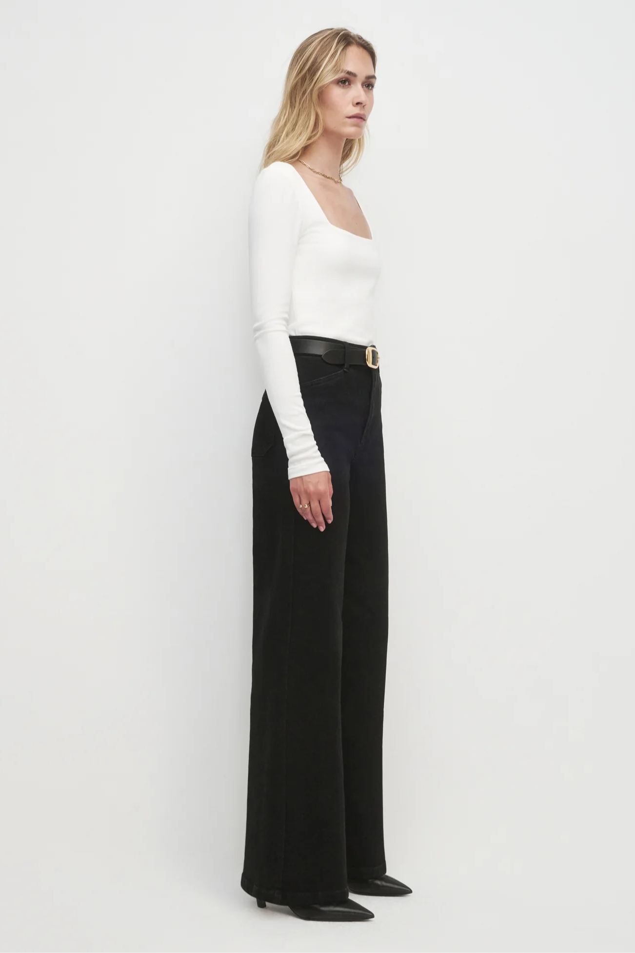 Woman wearing a white top and black pants on a white background