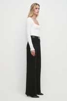 Woman wearing a white top and black pants on a white background