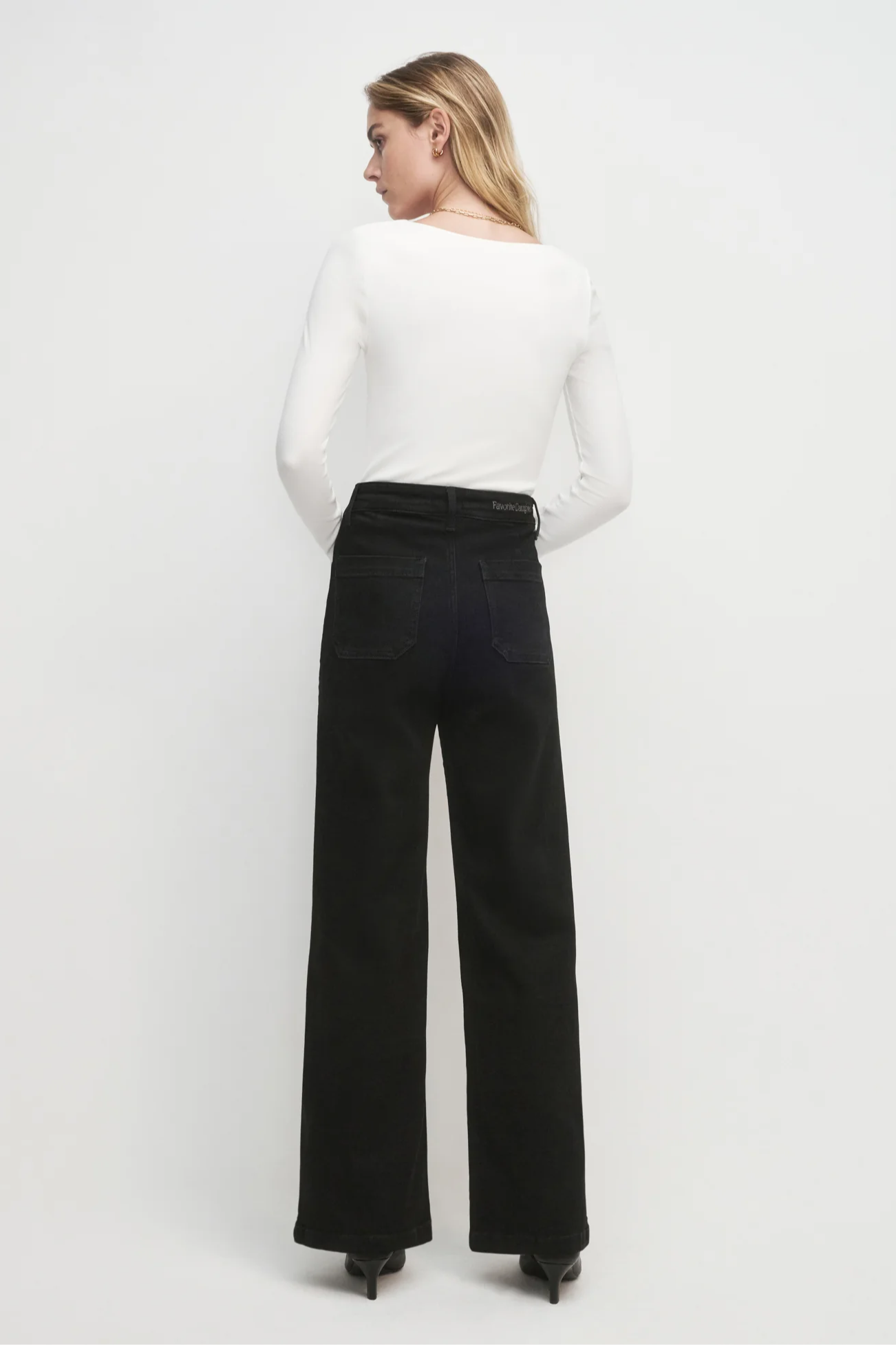 Woman wearing a white top and black pants on a white background