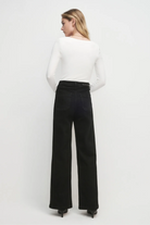 Woman wearing a white top and black pants on a white background