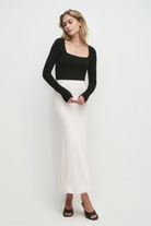Woman wearing a black top and white skirt on a white background