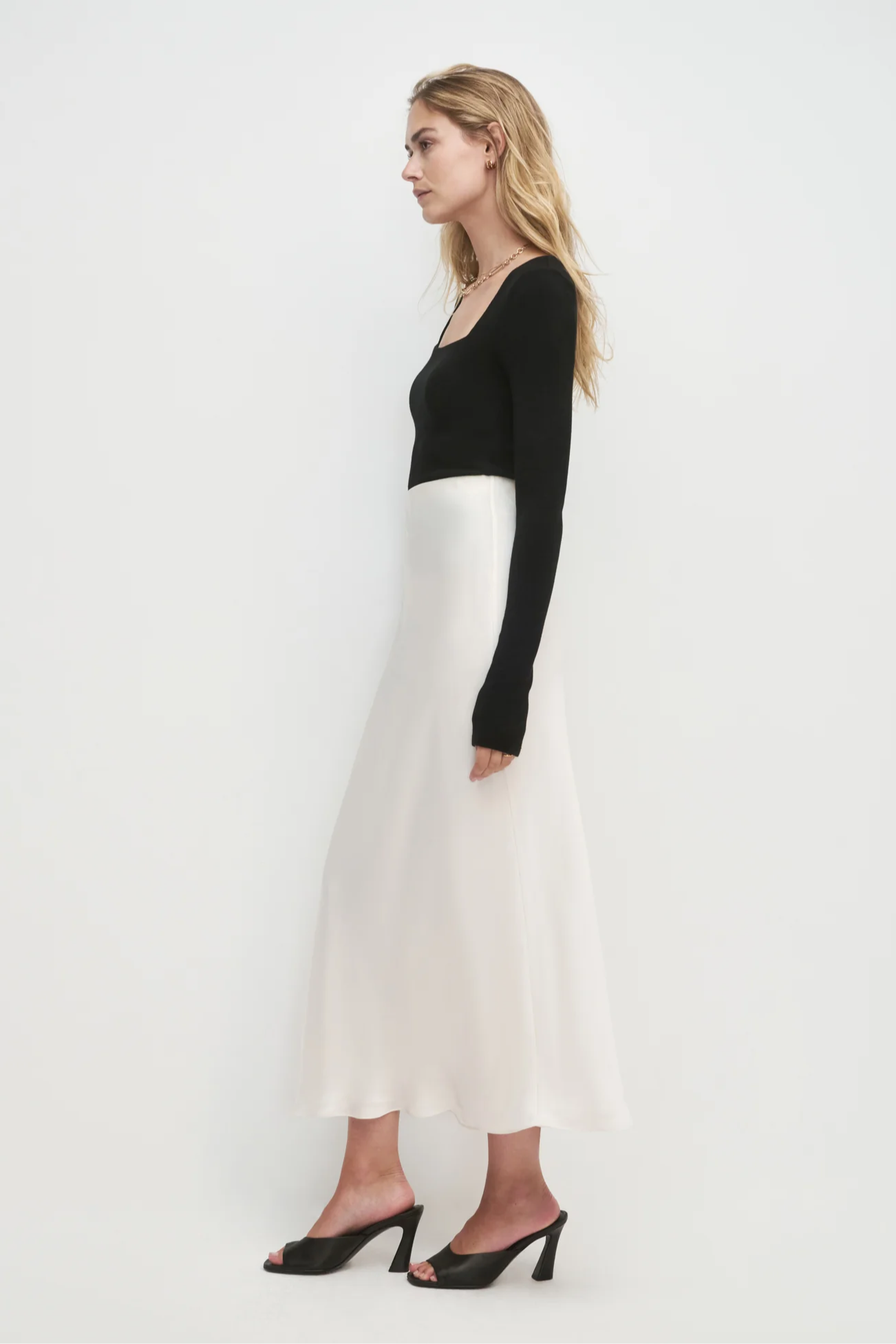 Woman wearing a black top and white skirt on a white background