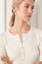 Woman wearing a cream ribbed cardigan against a white background