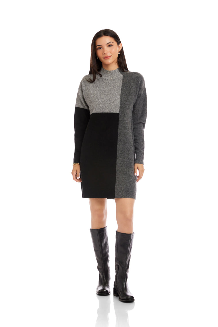 Woman wearing a gray and black color-blocked dress with black knee-high boots on a white background