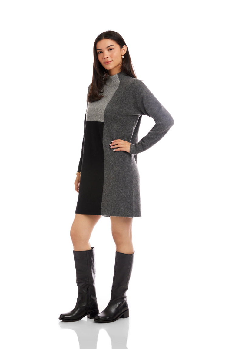 Woman wearing a gray and black dress with knee-high boots on a white background