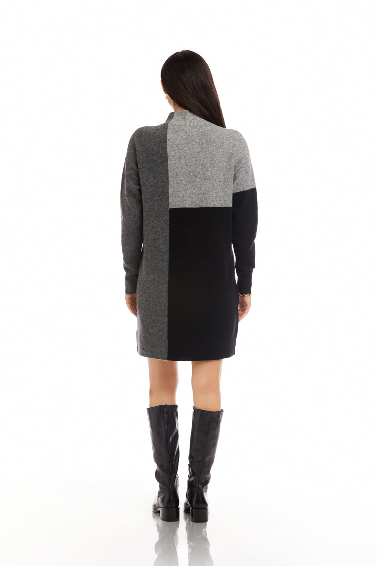 Woman wearing a gray and black dress with boots on a white background