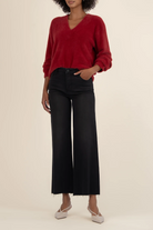 Person wearing a red sweater and black pants on a beige background