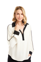 Woman wearing a white blouse with black trim on a white background