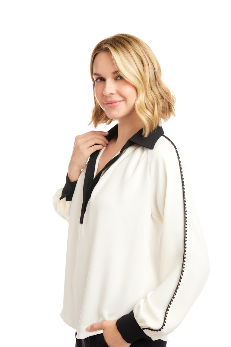 Woman wearing a white blouse with black trim on a white background