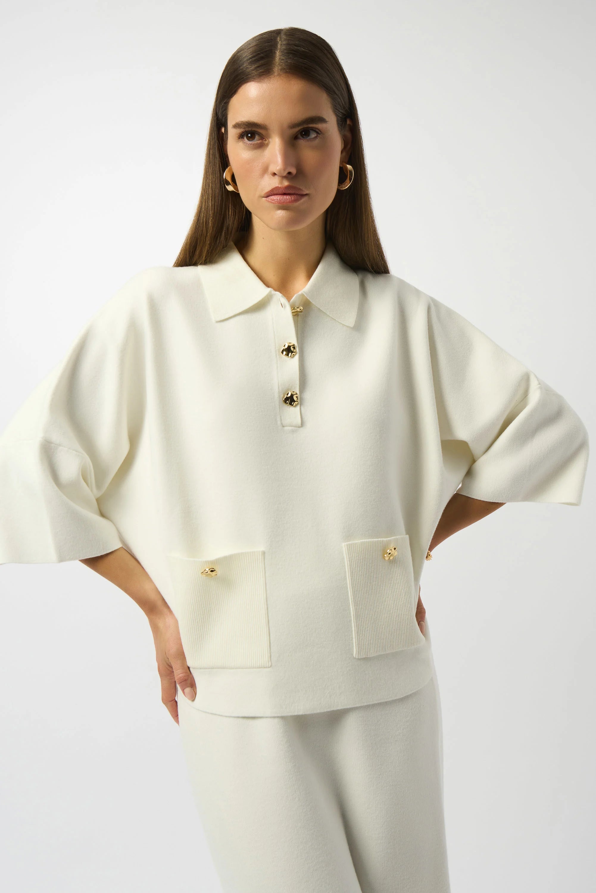 Woman wearing a white outfit with a collar on a plain background