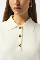 Close-up of a person wearing a white coat with gold buttons on a plain background