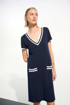 Woman wearing a navy dress with white accents on a white background