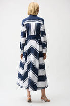 Woman wearing a long, navy and white striped dress on a white background