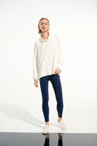 Person wearing a white hoodie and blue leggings on a white background