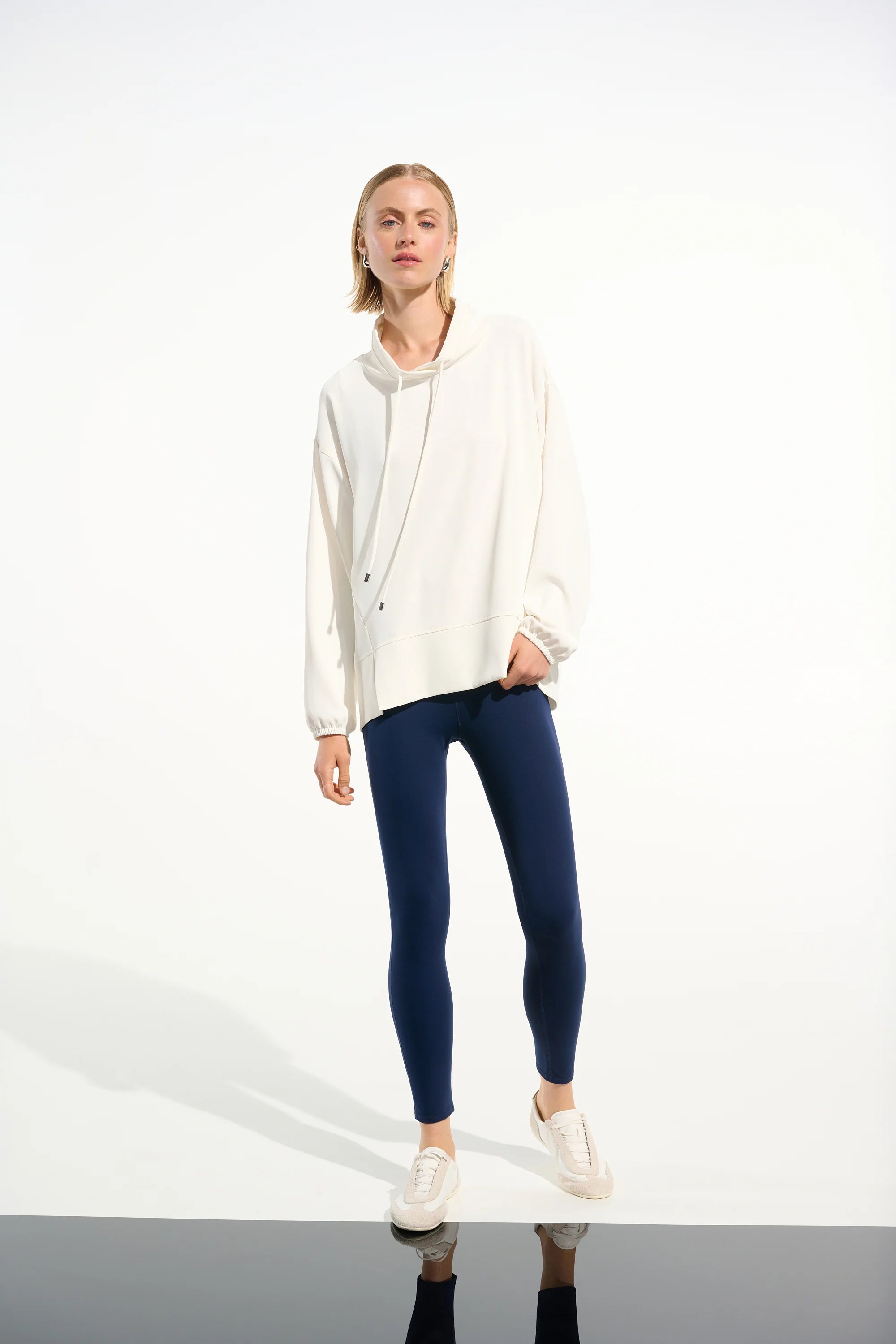 Person wearing a white hoodie and blue leggings on a white background